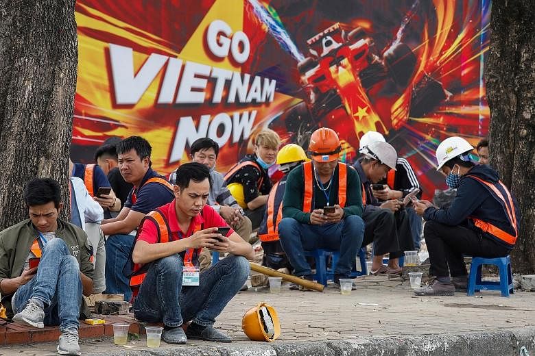 Workers taking a break in front of a poster promoting the Formula One Vietnam Grand Prix at the construction site of its racing track in Hanoi last Thursday. The event has been postponed.