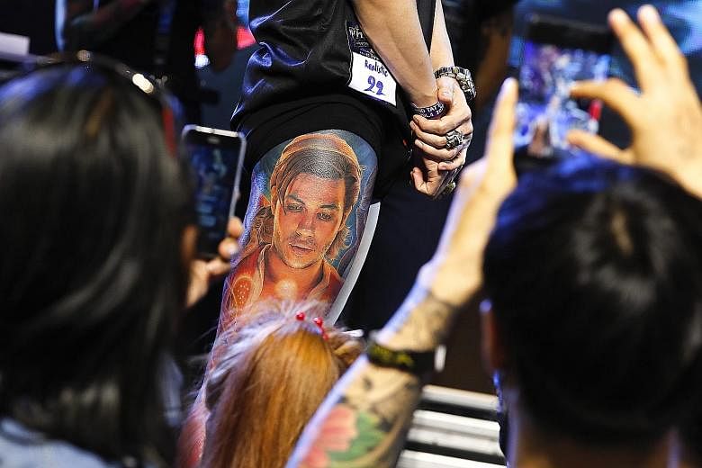 A man showing spectators his leg tattoo during a competition of realistic tattoos at Thailand Tattoo Expo 2020 in Bangkok last Saturday. Professional tattoo artists from 12 countries participated in the two-day event, both to get inked by fellow arti
