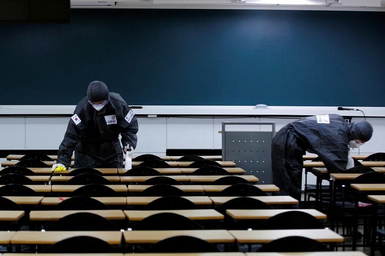 Soldiers cleaning desks with disinfectant in the classroom of a cram school for civil service examinations in Daegu, South Korea. The city has been declared a "special disaster zone", which means the government can subsidise up to 50 per cent of rest