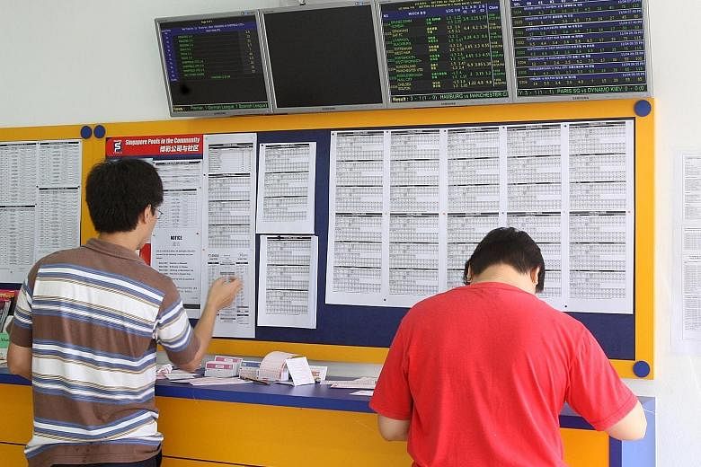 Punters at a Singapore Pools outlet. Legalised football betting was introduced in Singapore - and Asia - in 1999. SHIN MIN DAILY NEWS FILE PHOTO