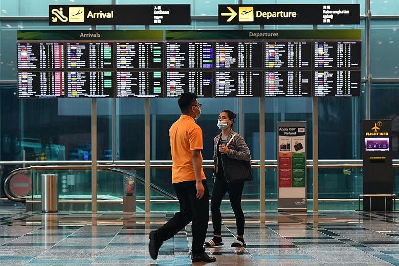 People wearing face masks at Changi Airport. National Development Minister Lawrence Wong pointed out yesterday that the majority of imported cases - which form the bulk of recent Covid-19 cases - are Singaporeans, permanent residents and long-term pa