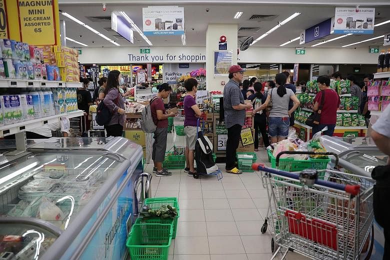 Shoppers at a FairPrice outlet in Toa Payoh yesterday. FairPrice said checkout queues were more orderly and customers were buying more responsibly than a similar episode early last month, when the national disease outbreak response level was raised t