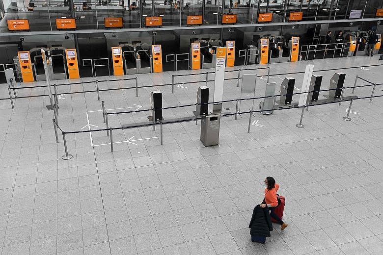 A woman wheeling her luggage through an empty check-in hall in Franz Josef Strauss airport in Munich, southern Germany, on Tuesday. Many flights have been cancelled by airlines because of the coronavirus and restrictions on travel by governments acro