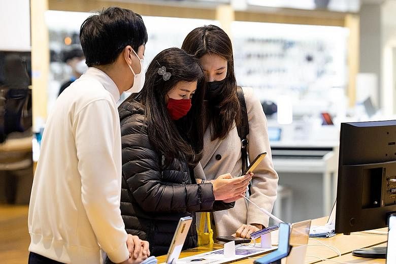 An employee (far left) attending to customers at Samsung Electronics' D'light flagship store in Seoul earlier this month. Samsung expects the coronavirus pandemic to hurt sales of smartphones and consumer electronics this year.