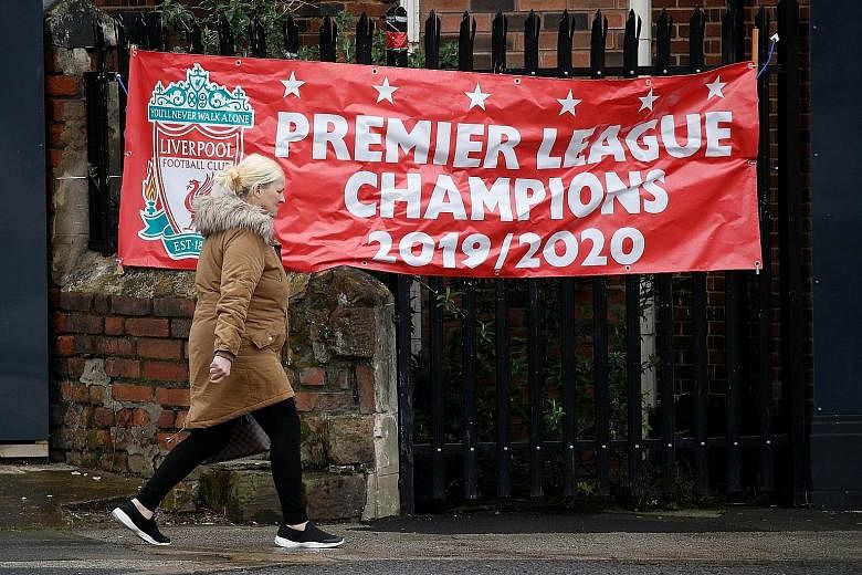 A woman in Liverpool walking past a banner proclaiming the Reds as champions of the Premier League. With a lead of 25 points over last season's winners Manchester City, the team need just two more wins for their first top-flight title in 30 years. Bu
