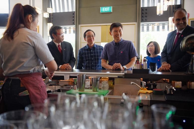 Mr Chee Hong Tat, Senior Minister of State for Trade and Industry as well as Education (centre), observing Fairmont Singapore hotel employee Isabella Lim, 29, concocting a cocktail at Prego restaurant yesterday.
