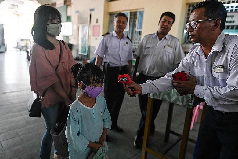A railway employee taking the temperature of a child as part of measures against the coronavirus at the central railway station in Yangon on Thursday. Myanmar has locked down its land borders, closed schools and put hospitals on standby. PHOTO: AGENC