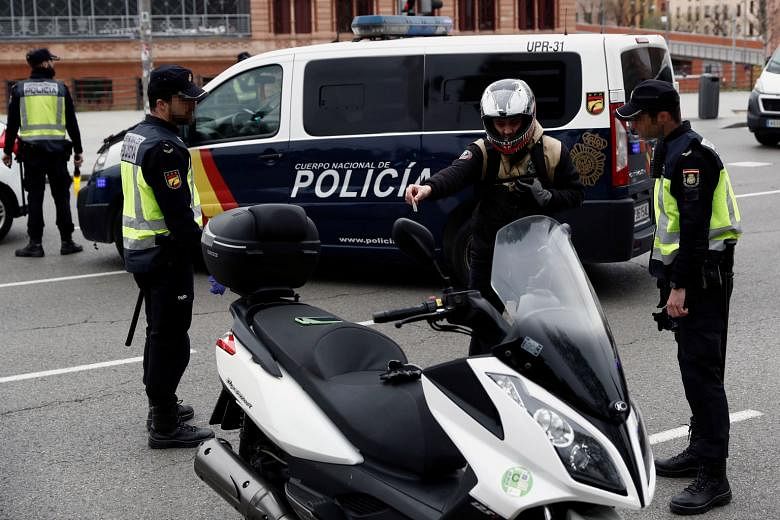 A motorcyclist being questioned by police at a checkpoint in downtown Madrid yesterday, as Spain faced the sixth day of a national lockdown. Workers tending to the bodies of coronavirus victims in the worst-hit province of Bergamo, in Italy, on Wedne