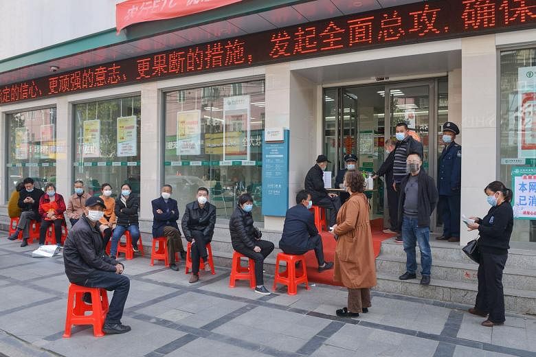 Customers queueing to have their temperature taken before entering a bank in Yunmeng county, in Xiaogan city, Hubei province, on Thursday. All 39 new coronavirus cases reported in China yesterday were imported. PHOTO: AGENCE FRANCE-PRESSE