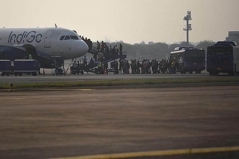 Passengers boarding an IndiGo aircraft at Indira Gandhi International airport in New Delhi. The Indian airline, which has the biggest domestic market share and an enviable profitable run, announced a pay cut for its senior employees last Thursday.