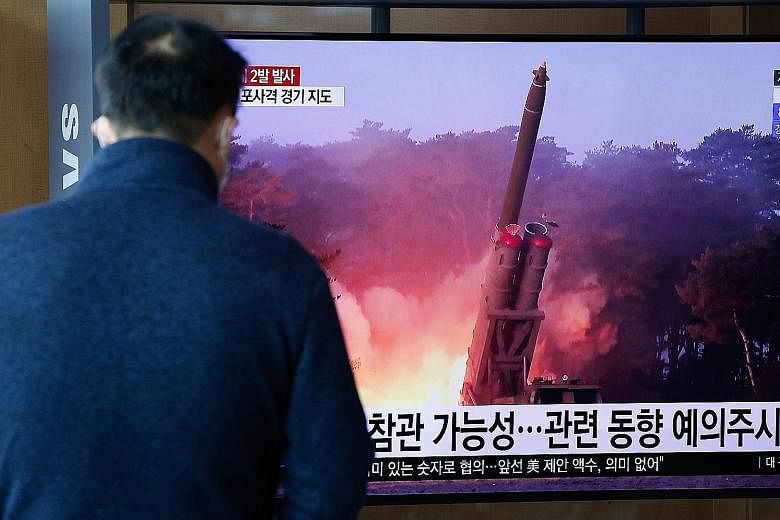 Above: A man in the South Korean capital Seoul watching breaking news of North Korea's projectile launch yesterday. Left: North Korea's leader Kim Jong Un watching an artillery fire contest with high-ranking military officers last Friday.