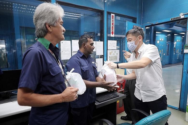 SPH deputy chief executive Anthony Tan giving out a care pack to senior printing staff member Alfred Saranapala at the company's Print Centre yesterday. With them was materials logistics assistant Kamarudin Idrus. Mr Tan was wearing a mask as he is i