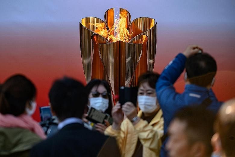 Members of the public in face masks taking photos of the sakura-shaped Olympic cauldron in front of the Sendai train station in north-eastern Japan.