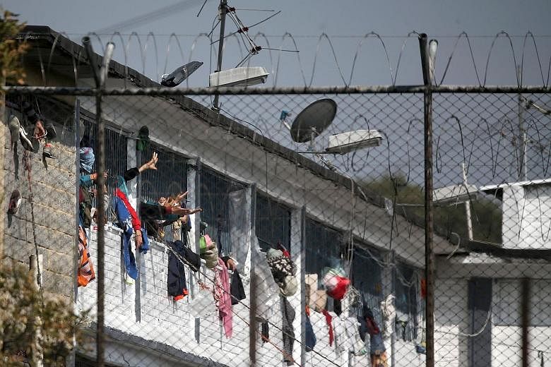 Inmates gesturing from their cells (above) at the Modelo prison in Bogota on Sunday after a riot the night before left 23 prisoners dead and 83 wounded. A man's body (left) is seen on the roof of a building inside the prison compound. The prisoners w