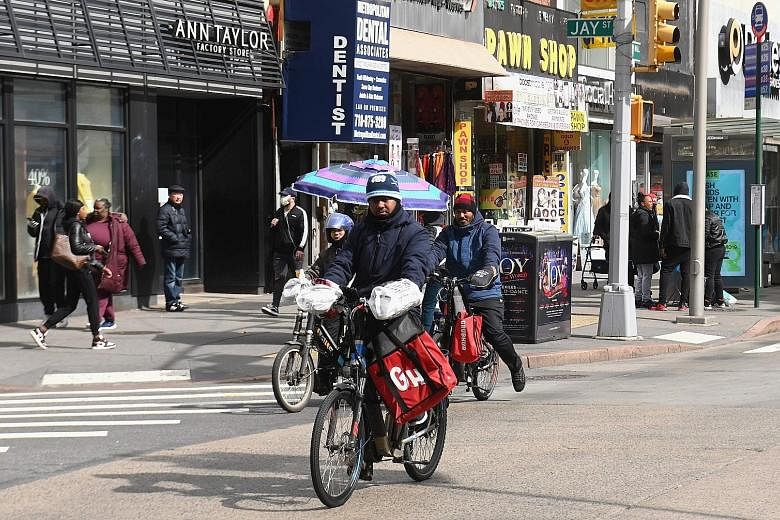 Food delivery riders in Brooklyn, New York. Many riders and drivers wear gloves and masks, and regularly apply disinfectant gel. Some wrap plastic around the handlebars of their bicycles.