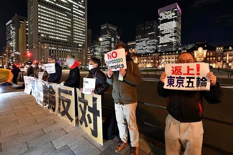 People opposed to the Tokyo 2020 Olympics holding placards during a rally in front of the Tokyo railway station yesterday. The International Olympic Committee bowed to mounting pressure to deliver its decision on the Tokyo Games, with athletes worldw