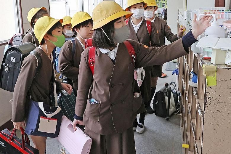 Japanese elementary schoolchildren at an Osaka school disinfecting their hands last month. Most schools in Japan are set to reopen on April 6, after a month-long closure to keep the virus spread in check. PHOTO: AGENCE FRANCE-PRESSE