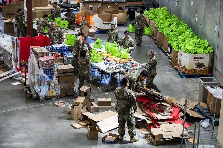 Soldiers packing donated food into bags that will be delivered to people in need at a food bank in Indio, California. The US' coronavirus relief package is expected to include a one-time direct payment of US$1,200 (S$1,730) per adult and US$500 per c