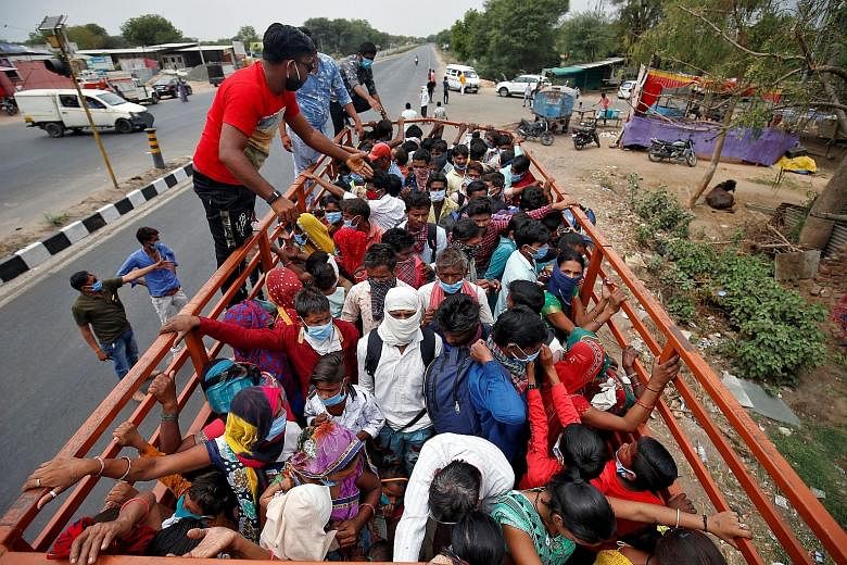 People practising social distancing while queueing outside a medical store in Allahabad yesterday. PHOTO: AGENCE FRANCE-PRESSE Migrant workers and their families boarding a truck to return to their villages yesterday after the lockdown in Ahmedabad. 