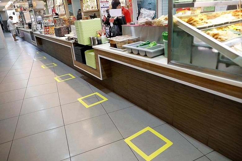 Social distancing markers outside Tangs department store in Orchard Road. Malls can stay open but have to abide by stricter precautions. Diners observing social distancing at a fast-food restaurant at Junction 8 mall yesterday. The lunchtime crowd at