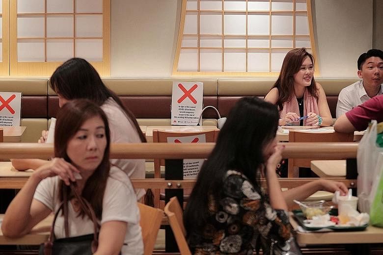 Social distancing markers outside Tangs department store in Orchard Road. Malls can stay open but have to abide by stricter precautions. Diners observing social distancing at a fast-food restaurant at Junction 8 mall yesterday. The lunchtime crowd at