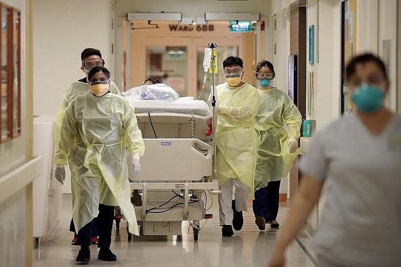 Left: Healthcare workers in the Singapore General Hospital isolation ward assisting in the transfer of a suspected Covid-19 patient to an isolation room. Singapore yesterday reported 52 new coronavirus cases. ST PHOTO: NEO XIAOBIN Above: Deputy Prime