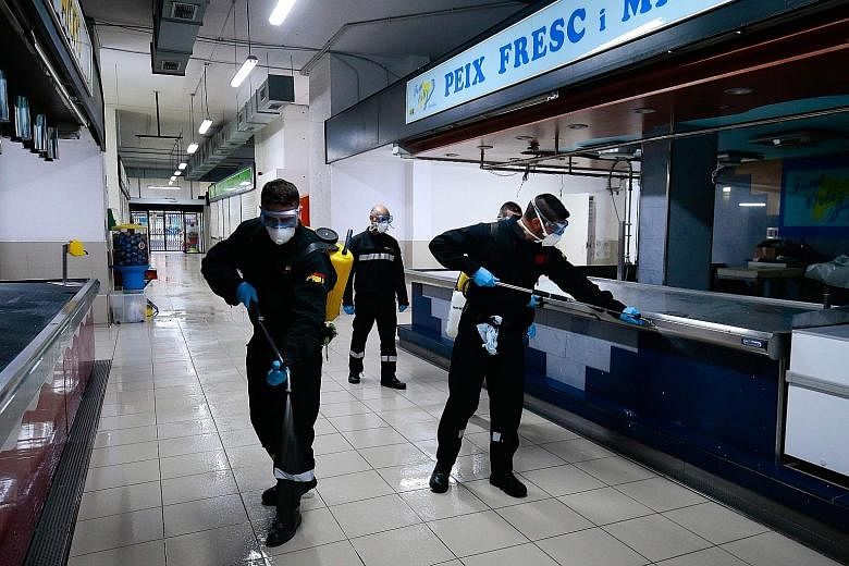 Members of Spain's Military Emergencies Unit carrying out general disinfection at a local market in Badalona, near Barcelona, on Wednesday. PHOTO: AGENCE FRANCE-PRESSE