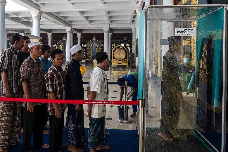 Indonesians have to walk through a disinfectant chamber before entering a mosque during Friday prayers yesterday in Surabaya, East Java, as a measure to stop the spread of the coronavirus. PHOTO: AGENCE FRANCE-PRESSE