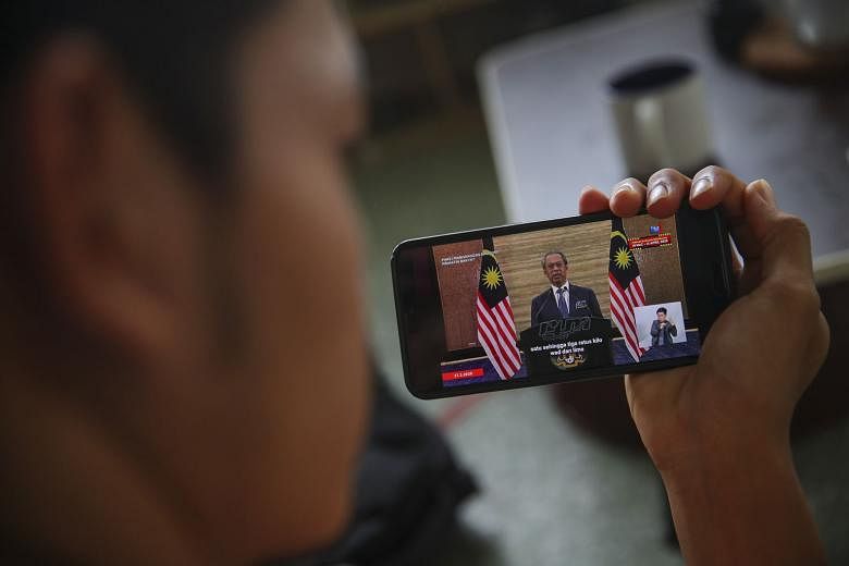 A journalist watching a live telecast of Malaysian Prime Minister Muhyiddin Yassin's speech on the "people-centric stimulus package" in Kuala Lumpur yesterday. PHOTO: EPA-EFE