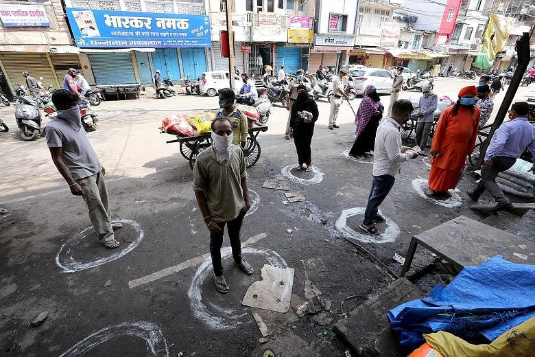People standing in designated spots in Bhopal, India, yesterday to maintain social distancing as they queued outside a general store during a government-imposed 21-day nationwide lockdown, which has been put in place to fight the coronavirus outbreak