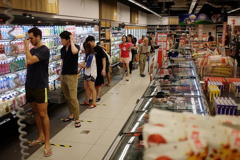 Shoppers at Tiong Bahru Plaza yesterday, the first Saturday after stricter measures were put in place to curb the spread of the coronavirus, requiring malls to limit customer numbers and disperse groups of more than 10. Left: Shoppers in a queue at a