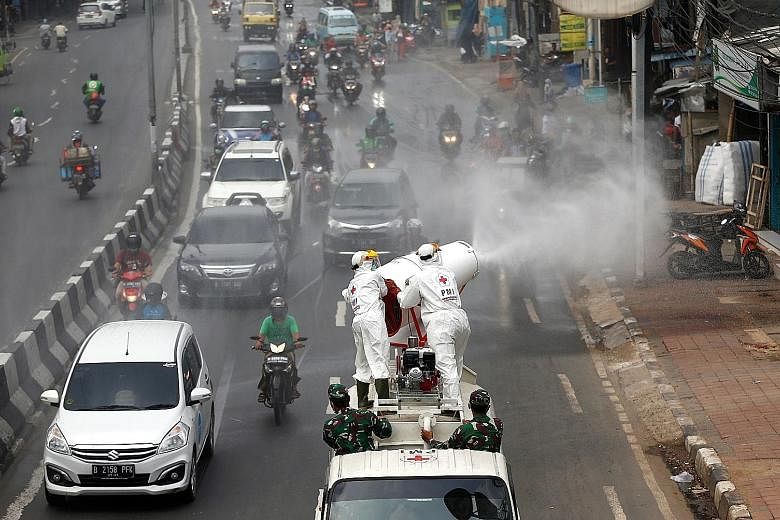 Red Cross personnel in protective suits spraying disinfectant from a vehicle in Jakarta yesterday to prevent the spread of the coronavirus outbreak. Jakarta has a total of 627 cases, and 62 people have died. PHOTO: REUTERS