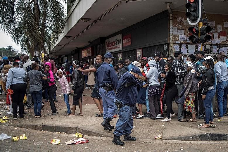 A South African policeman pointing a pump rifle at shoppers in Yeoville, Johannesburg, yesterday, in an attempt to enforce safe-distancing rules outside a supermarket amid the coronavirus pandemic. PHOTO: AGENCE FRANCE-PRESSE