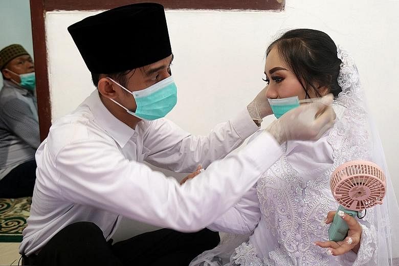 A groom puts a face mask on his bride before their wedding ceremony in Jakarta. The wedding proceeded on Saturday amid concerns about the coronavirus outbreak, which has led the government to consider a lockdown of the capital.
