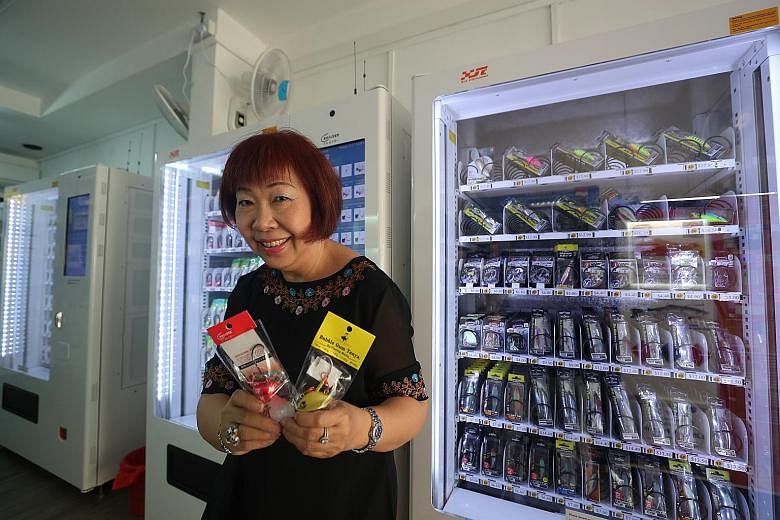 Ms Elizabeth Lai with fishing tackle that can be purchased from vending machines at her Clementi West shop. ST PHOTO: TIMOTHY DAVID