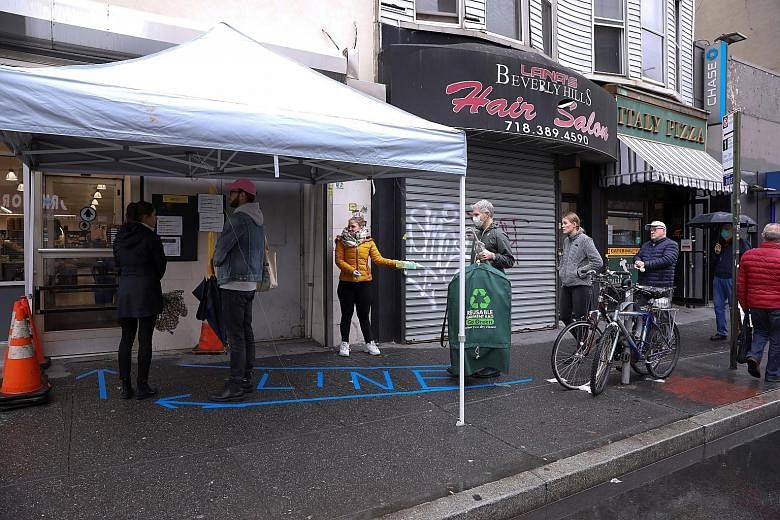 People practising social distancing while waiting in line outside a grocery store in Brooklyn, New York, on Saturday. The death count in the United States has crossed 2,200, more than double the level from two days ago.
