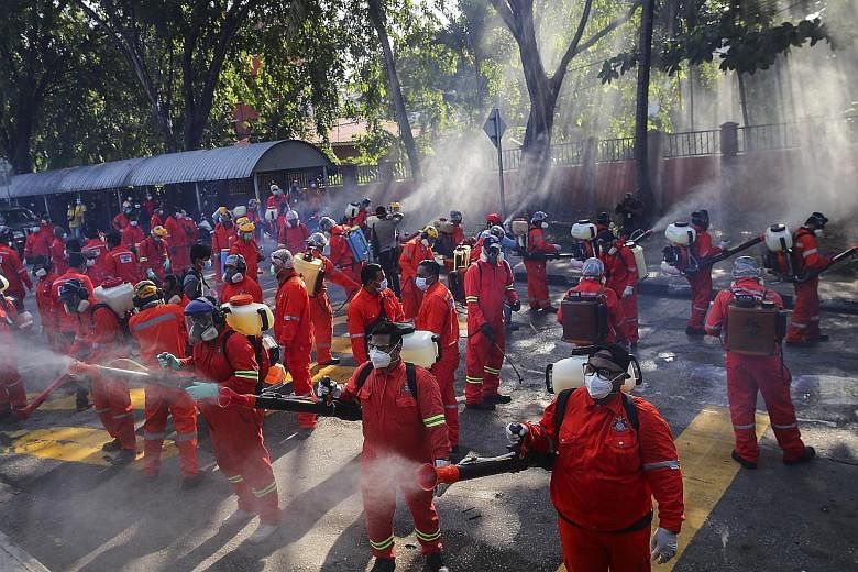 City Hall health officials disinfecting the entrance of the Sri Petaling mosque in Kuala Lumpur last Saturday. A religious gathering at the mosque last month led to the spread of most of Malaysia's coronavirus infections. PHOTO: EPA-EFE