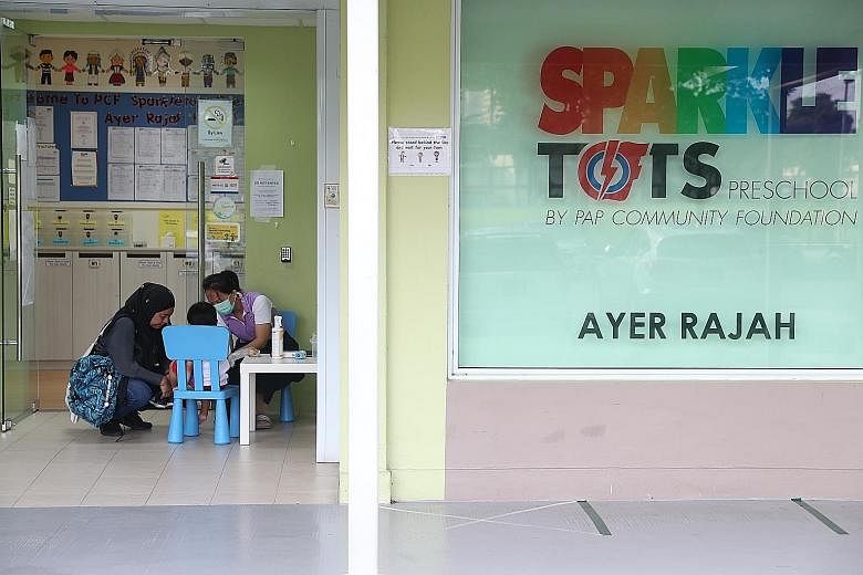 Logistics executive Siti Hajar, 42, accompanying her son, three-year-old Mohd Luthfi, as he had his temperature taken at PCF Sparkletots Preschool@Ayer Rajah in Teban Gardens Road yesterday. Some 21,393 children were back at the Sparkletots centres y
