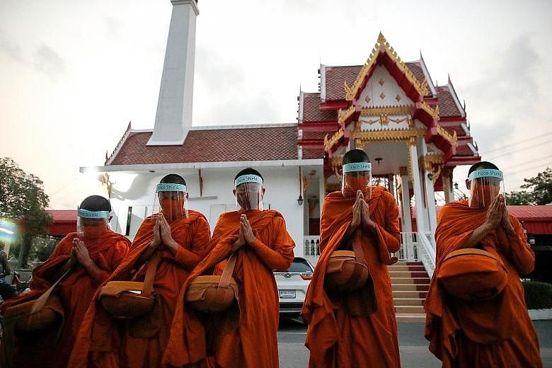 Buddhist monks wearing masks and face shields as they collected alms in Bangkok on Tuesday. PHOTO: EPA-EFE