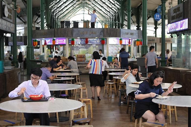Office workers at Lau Pa Sat practising safe distancing during lunchtime yesterday. Other popular lunch spots near Cross Street, Boon Tat Street and Robinson Road were less than half full, partly due to marked seats for social distancing. ST PHOTO: O