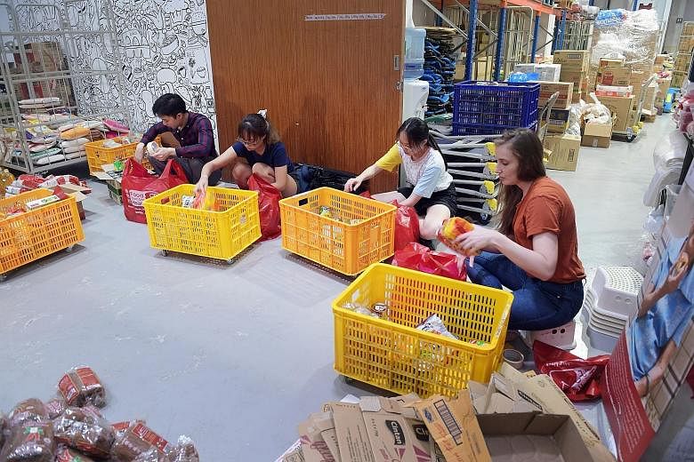 Food From The Heart volunteers and staff packing food at their Joo Seng Road warehouse yesterday for distribution to the needy.