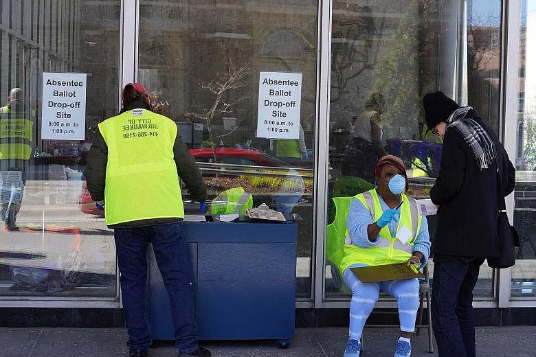 Volunteers in protective gear assisting a voter at an early voting ballot drop-off location in Milwaukee, Wisconsin, on Thursday. The US is working out how to hold the Nov 3 presidential polls amid the Covid-19 pandemic.