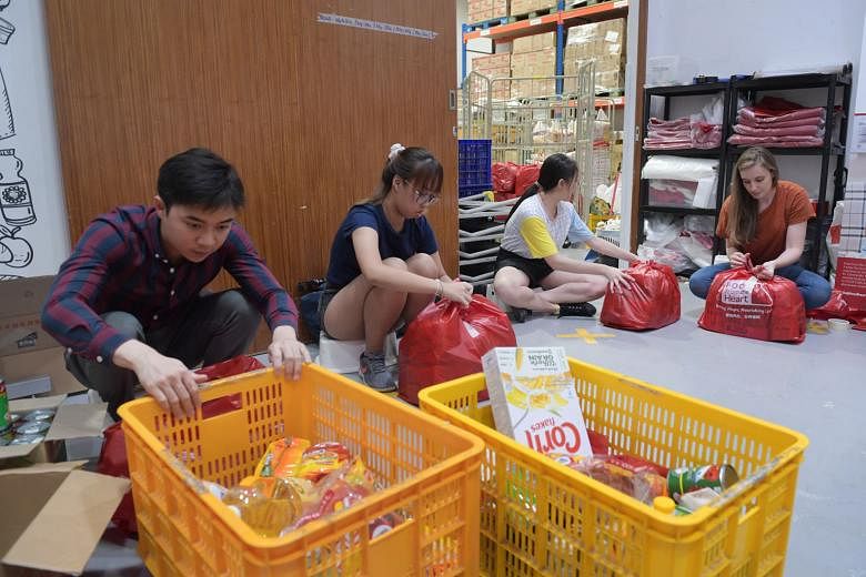 Food From The Heart staff and volunteers packing food at its warehouse in Joo Seng Road yesterday for distribution to the needy. Before the coronavirus outbreak, the charity had about 60 volunteers a day helping to prepare the food packs, but the num