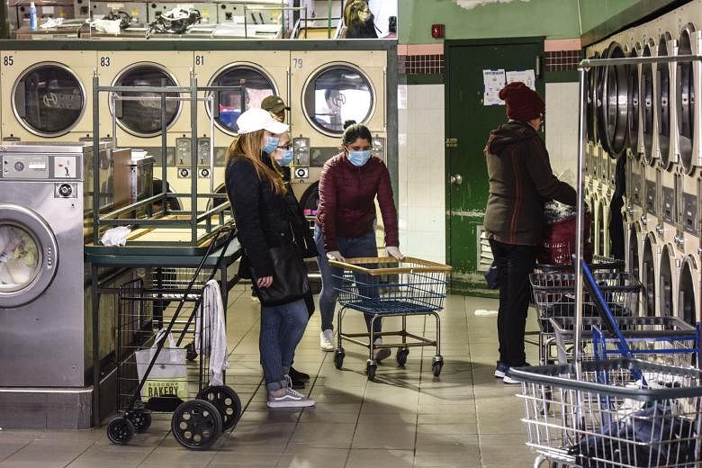 People wearing masks at a launderette on Tuesday, in Brooklyn, New York City, the epicentre of the outbreak in the United States.