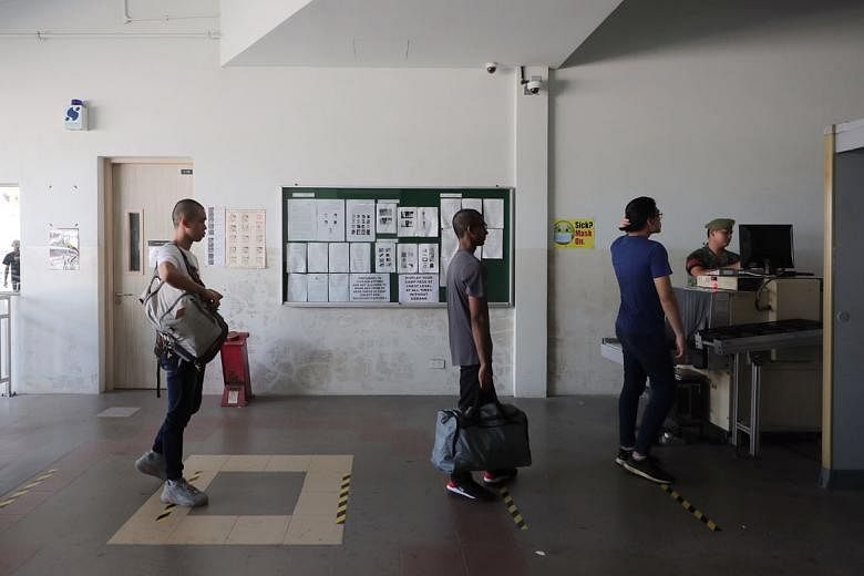 Newly enlisted national servicemen queueing for security checks while practising social distancing at the SAF Ferry Terminal before heading to Pulau Tekong on Wednesday. Defence Minister Ng Eng Hen said yesterday that the SAF has to continue to safeg