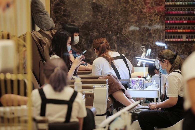 Some shoppers enjoying a pedicure (top) at VivoCity yesterday while others had their hair done (above). While hair salons can still remain open to offer basic haircuts, salons offering services such as hair-colouring treatments, manicures and facials