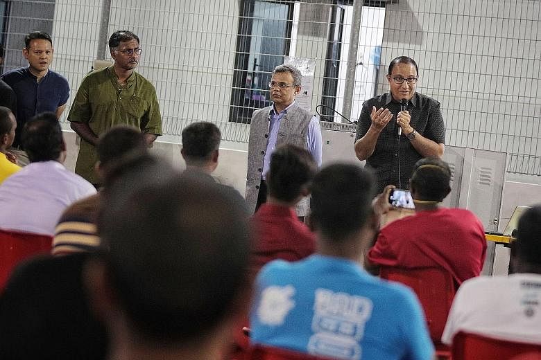 Minister for Communications and Information S. Iswaran (far right) speaking to migrant workers to assuage their concerns at Westlite Papan dormitory in Jurong yesterday. With him are (from left) Minister of State for Manpower Zaqy Mohamad, Bukit Bato