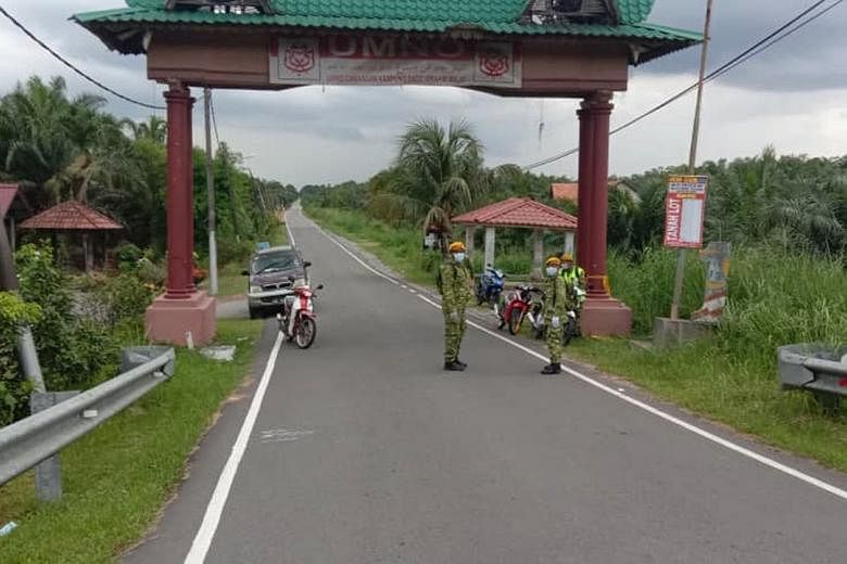 Volunteer corps members on duty at a sealed-off access road to Kampung Datuk Ibrahim Majid, one of the first two areas in Malaysia to be placed under total lockdown after a spike in coronavirus cases. 
