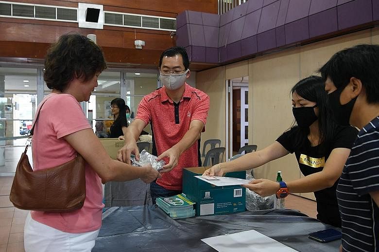 Residents collecting reusable masks at Potong Pasir Community Cub yesterday. At collection points, safe distancing measures were in place for people in the queues, and temperature taking was done before residents could enter the premises. ST PHOTO: K
