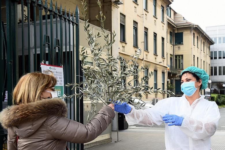 A field hospital being built outside La Fe Hospital in Valencia, Spain, to admit Covid-19 patients. PHOTO: AGENCE FRANCE-PRESSE A nurse at Molinette Hospital in Turin, Italy, receiving a bunch of palm tree branches from a woman entering the premises 